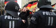 Ein mann mit Deutschlandflagge steht vor Polizisten