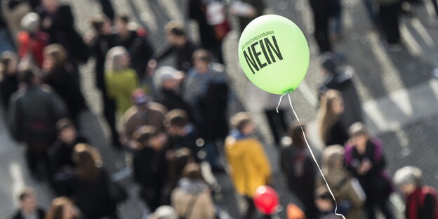 Ballon mit Aufschrift "Nein!" fliegt über einer Menschenmenge