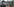 Ein Mann mit Hut und Brille hält eine Videokamera