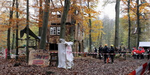 Polizisten neben einem provisorischen Holzhaus