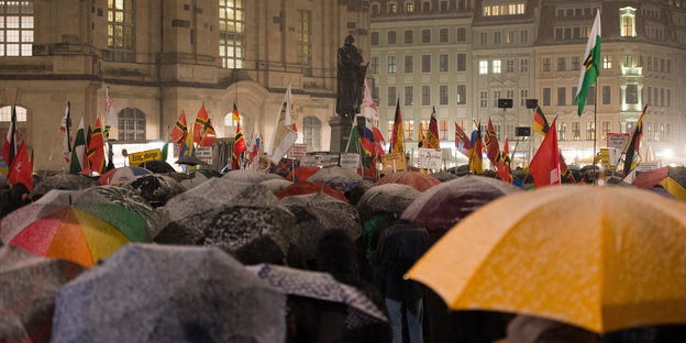 Pegida-Anhänger in Dresden mit Schirmen und Deutschlandfahnen