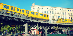 Eine gelbe Bahn fährt die Hochtrasse am Schlesischen Tor in Berlin entlang.