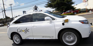 Ein weißes Auto mit der Aufschrift "Google" auf einer Straße
