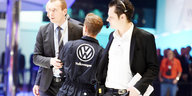 Männer halten einen anderen Mann in VW-Anzug am Arm fest.