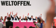 SPD-Politiker_innen hälten rosafarbene Stimmkarten in die Höhe, hintern ihnen der Schriftzug „Weltoffen.“.