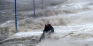 Zwei Männer halten sich am 05.12.2013 während einer Sturmflut, verursacht durch das Orkantief «Xaver», auf dem überfluteten Fähranleger in Dagebüll an einem Geländer fest