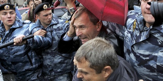Volker Beck versteckt sich unter einem roten Regenschirm