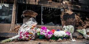 Blumen vor einem verkohlten Haus