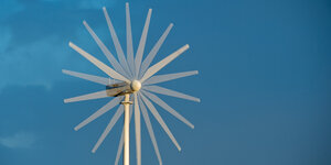 Ein laufendes Windrad steht vor einem blaunen Himmel