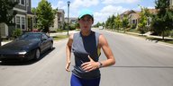 Ein Frau joggt auf einer sommerlichen Straße