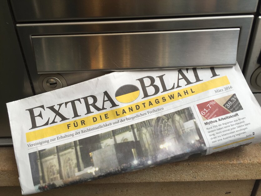 Ein zeitungsähnliches Blatt steckt in einem Briefkasten, darauf die Aufschrift: Extra-Blatt.