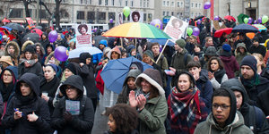 Die Demonstrationsteilnermer*innen mit Regenschirmen am Rosa-Luxemburg-Platz in Berlin