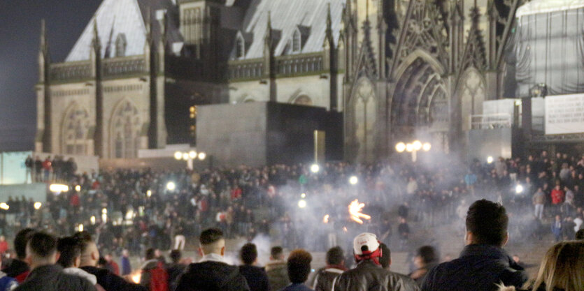 Eine Menschenmasse bei Nacht vor einem beleuchteten Dom.