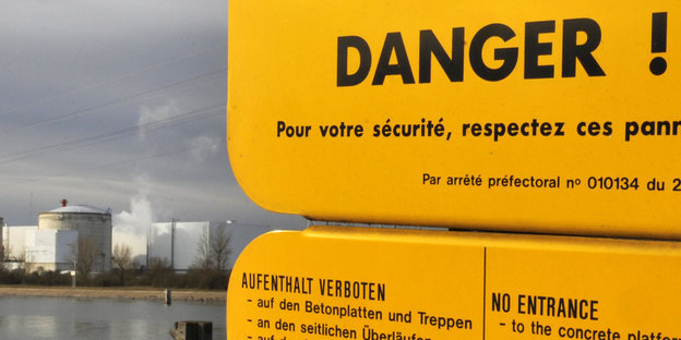 Ein gelbes Schild warnt °Danger!“, dahinter liegt das AKW Fessenheim.