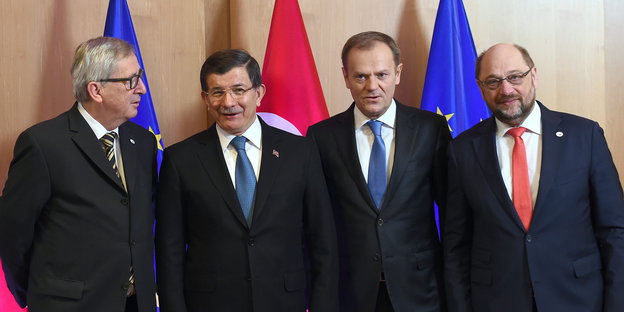 vier Männer in Anzügen vor EU- und Türkeifahnen