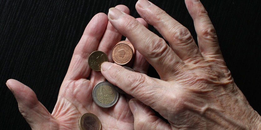 In einer Hand liegen Münzen, die andere Hand zählt diese