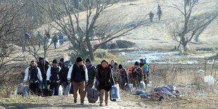 Menschen mit Gepäck laufen durch eine winterliche Landschaft