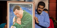 Präsident Maduro hält ein Gemälde hoch, auf dem der ehemalige Präsident Chavez seine Mutter umarmt