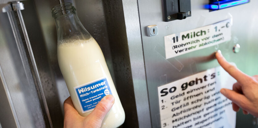 Eine Hand hält eine Milchflasche unter den Zapfhahn einer Milchtankstelle