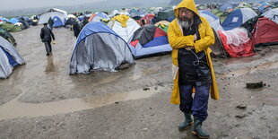 Ein Mann im Regencape vor Zelten