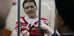 Eine Frau mit dunklen Haaren, Sawtschenko, lässt sich die Handschellen anlegen