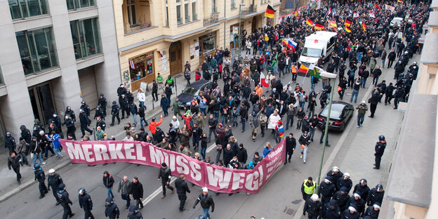 Schwarz angezogene Menschen demonstrieren mit einem rosafarbenen Banner