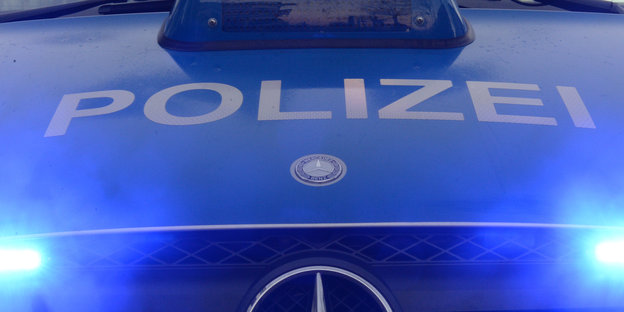 Der Schriftzug "Polizei" ist auf einem Polizeifahrzeug mit Blaulicht zu sehen.