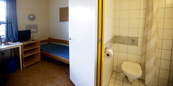 Links öffnet sich eine Tür zu einem Zimmer mit Bett, Schreibtisch und Fenster, rechts ist ein Bad mit WC und Dusche zu sehen.