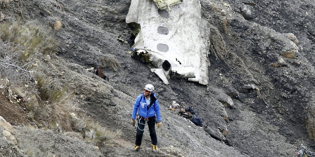 Ein Mann mit Kletterausrüstung vor einem Flugzeugteil
