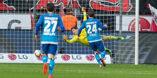 Zwei Fußballspieler vor einem Tor, der Torwart versucht, einen Ball zu erreichen