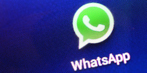 Auf einem Bildschirm ist das grüne Logo von WhatsApp zu sehen.