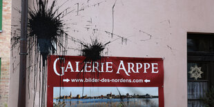 Schwarze Farbkleckse auf einer rosafarbenen Hauswand und einem Schild „Galerie Arppe“.