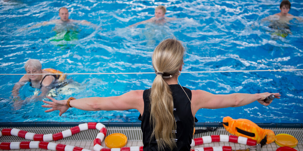 Eine Frau mit ausgestreckten Armen vor einem Pool