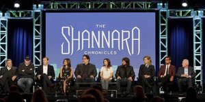 Menschen sitzen in einer Reihe vor einem Bildschirm mit der Aufschrift: „The Shannara Chronicles“.