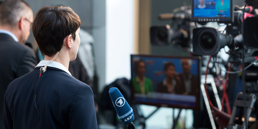 Frauke Petry ist von hinten zu sehen. Sie steht vor Kameras.