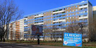 ein Plattenbau bei sonnigem Wetter, im Vordergrund ein Wahlplakat der AfD mit dem Slogan „Es reicht - Sachsen-Anhalt wählt AfD“