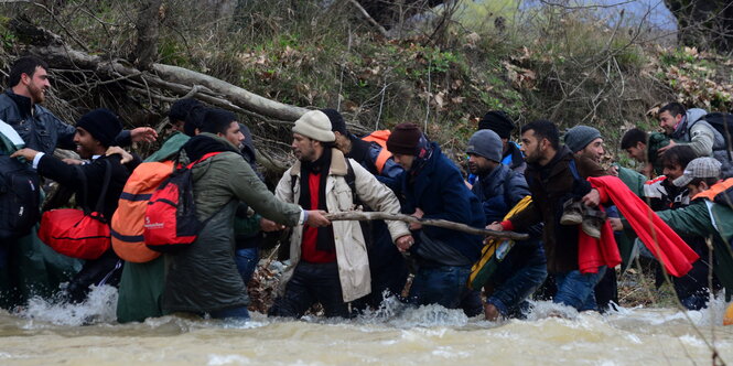 Menschen warten durch einen Fluss.