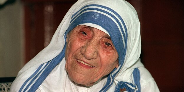 Eine alte Frau mit einem Blau-weißen Kopftuch und Gewand.