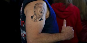 Auf einem nackten weißen Oberarm prangt Donald Trumps Porträt.