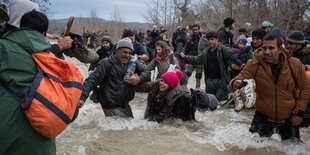 Menschen stehen in einem Fluss mit reißendem Wasser