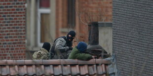 Polizisten mit Tarnmasken und Gewehren auf einem Dach.