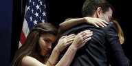 Tochter, Frau und Mann umarmen sich, im Hintergrund USA-Flagge