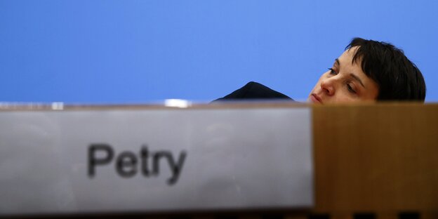 Frauke Petry duckt sich hinter dem Pult der Bundespressekonferenz, so dass nur noch ihr Kopf zu sehen ist.