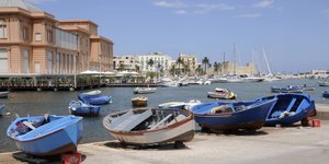 Im Hafen von Bari liegen mehrere kleine Boote unter blauem Himmel