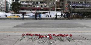 Eine Straßenansicht. Rosen liegen auf dem Bürgersteig