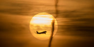 Ein gelblicher Morgenhimmel mit Sonne und Flugzeug
