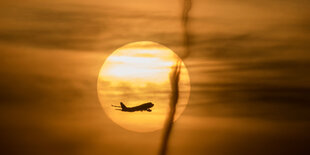 Ein gelblicher Morgenhimmel mit Sonne und Flugzeug