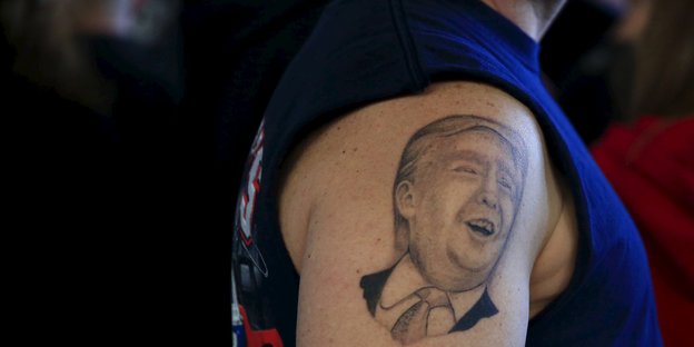 Auf einem Oberarm ist ein Tattoo zu sehen, das Donald Trump darstellt
