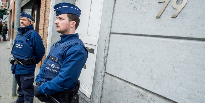 Zwei Polizisten stehen vor einem Haus