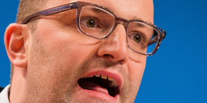 Ein weißer Mann mit Brille reißt den Mund weit auf